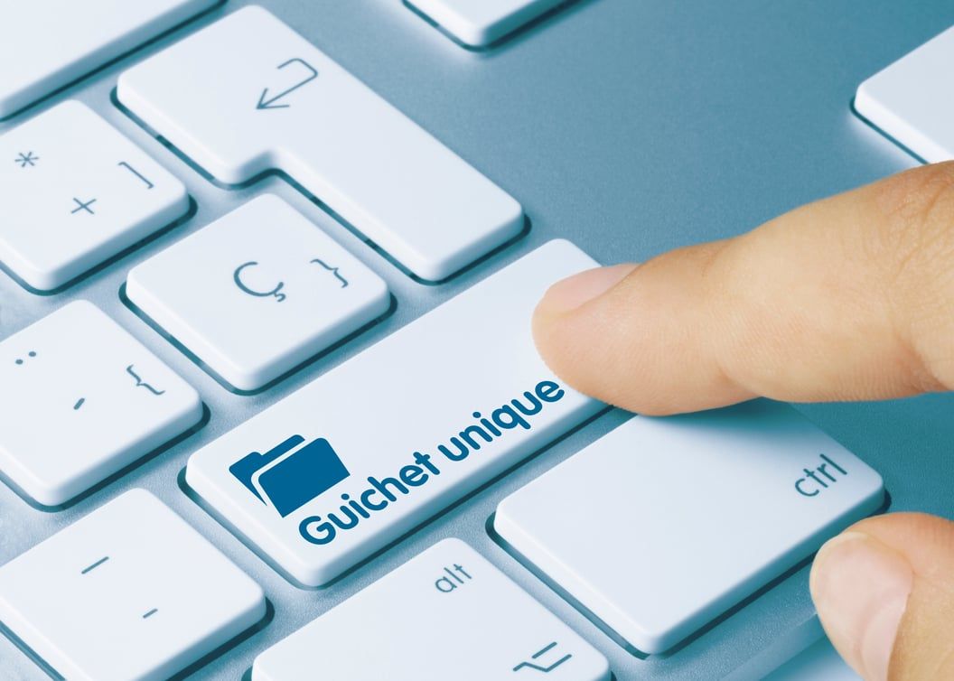 Un doigt appuyant sur une touche de clavier marquée d'une icône de dossier intitulée « Guichet unique »