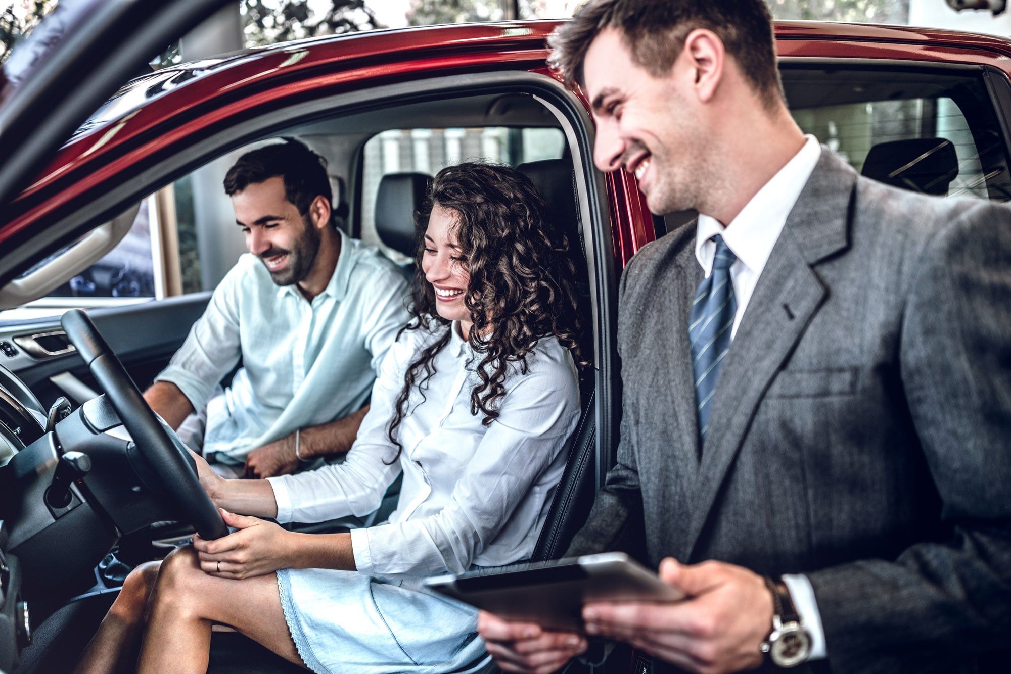 A salesperson showing a car to customers in a dealership