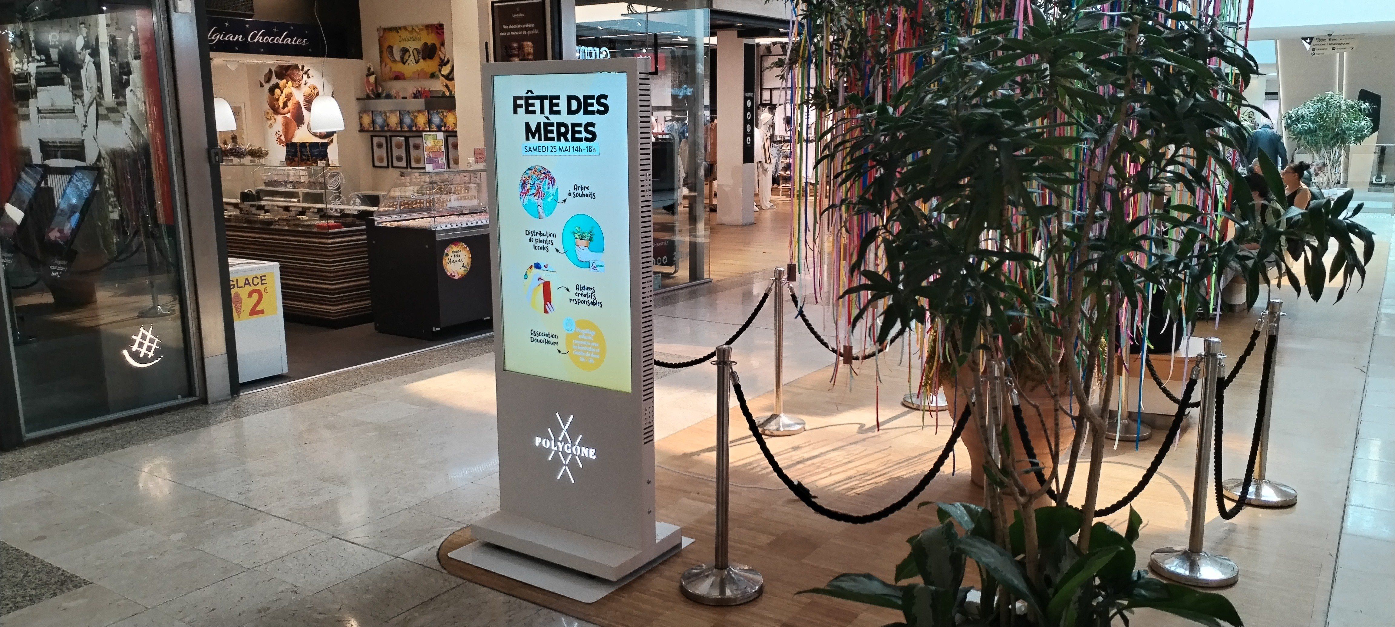 The touch table terminal beside the tall digital signage totem in the mall