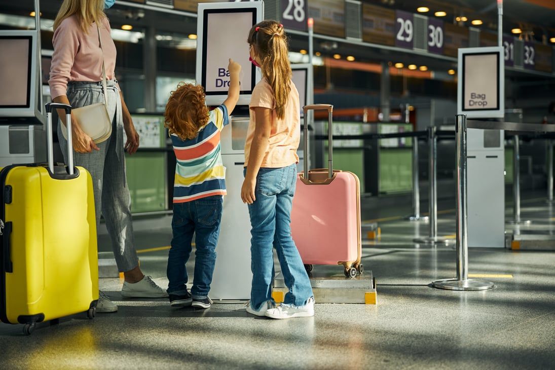 Travelers with luggage in front of airport information screens