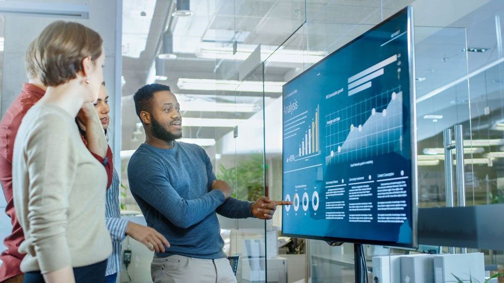 Des collègues consultant des indicateurs sur un grand écran mural