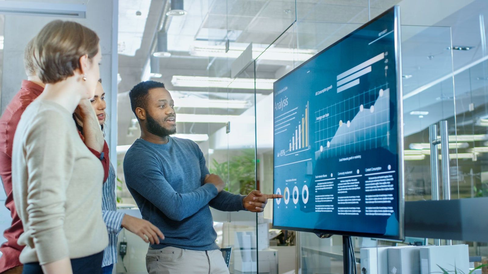 Colleagues reviewing charts on a large wall-mounted screen